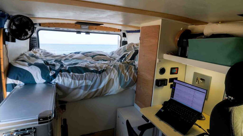 Ram Promaster camper van interior shot with desk and bed
